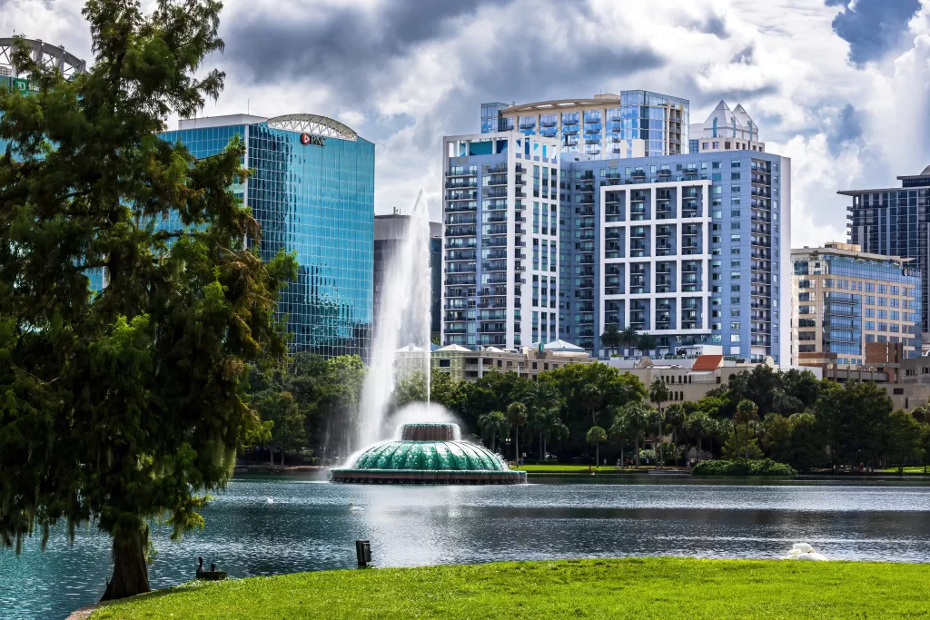 Downtown Orlando skyline behind the Lake Eola fountain under dramatic skies.
